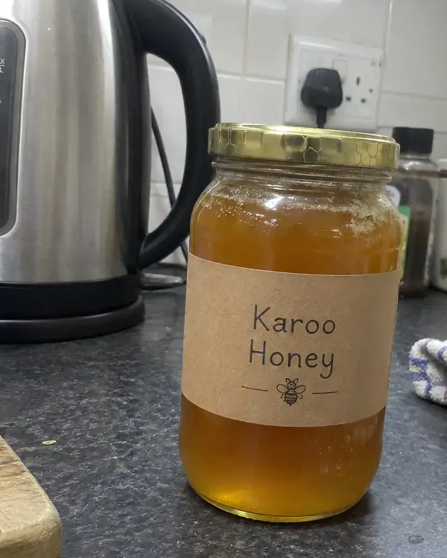 Phone photo of a Karoo Honey jar next to a kettle on a kitchen counter